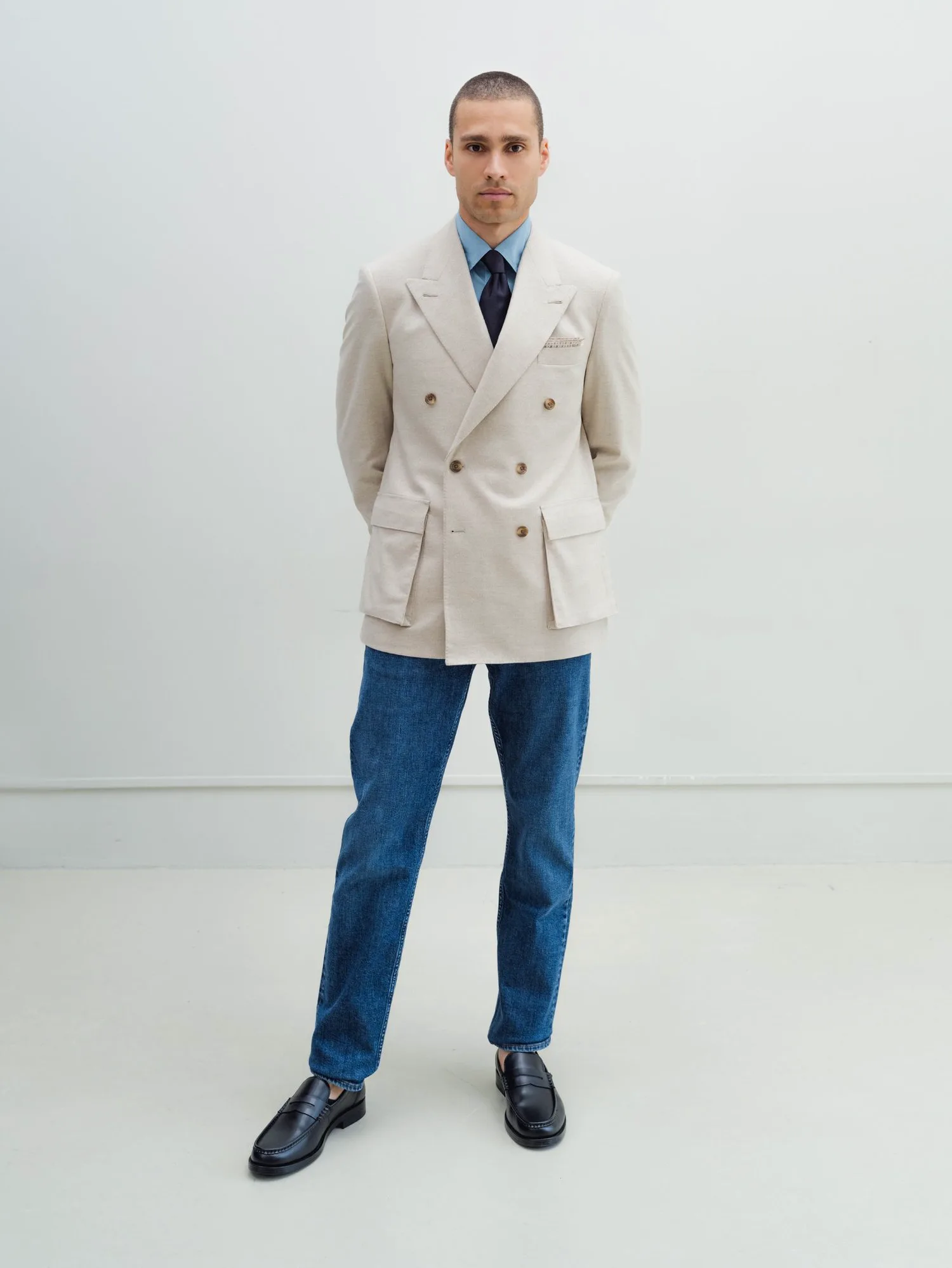 Man in a white double-breasted jacket and dark jeans