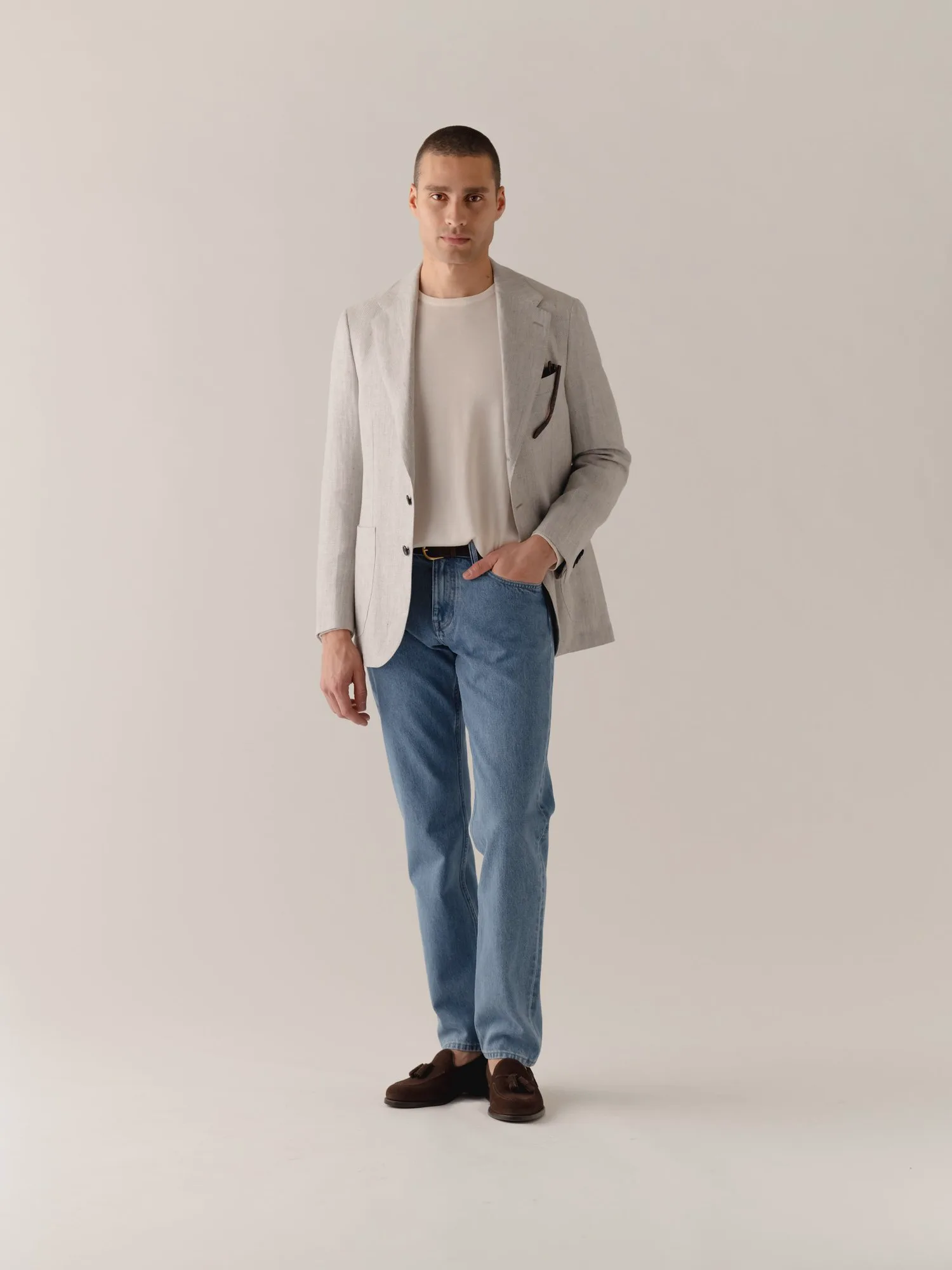 Mand i lys, ustruktureret jakke, hvid T-shirt og smalle jeans