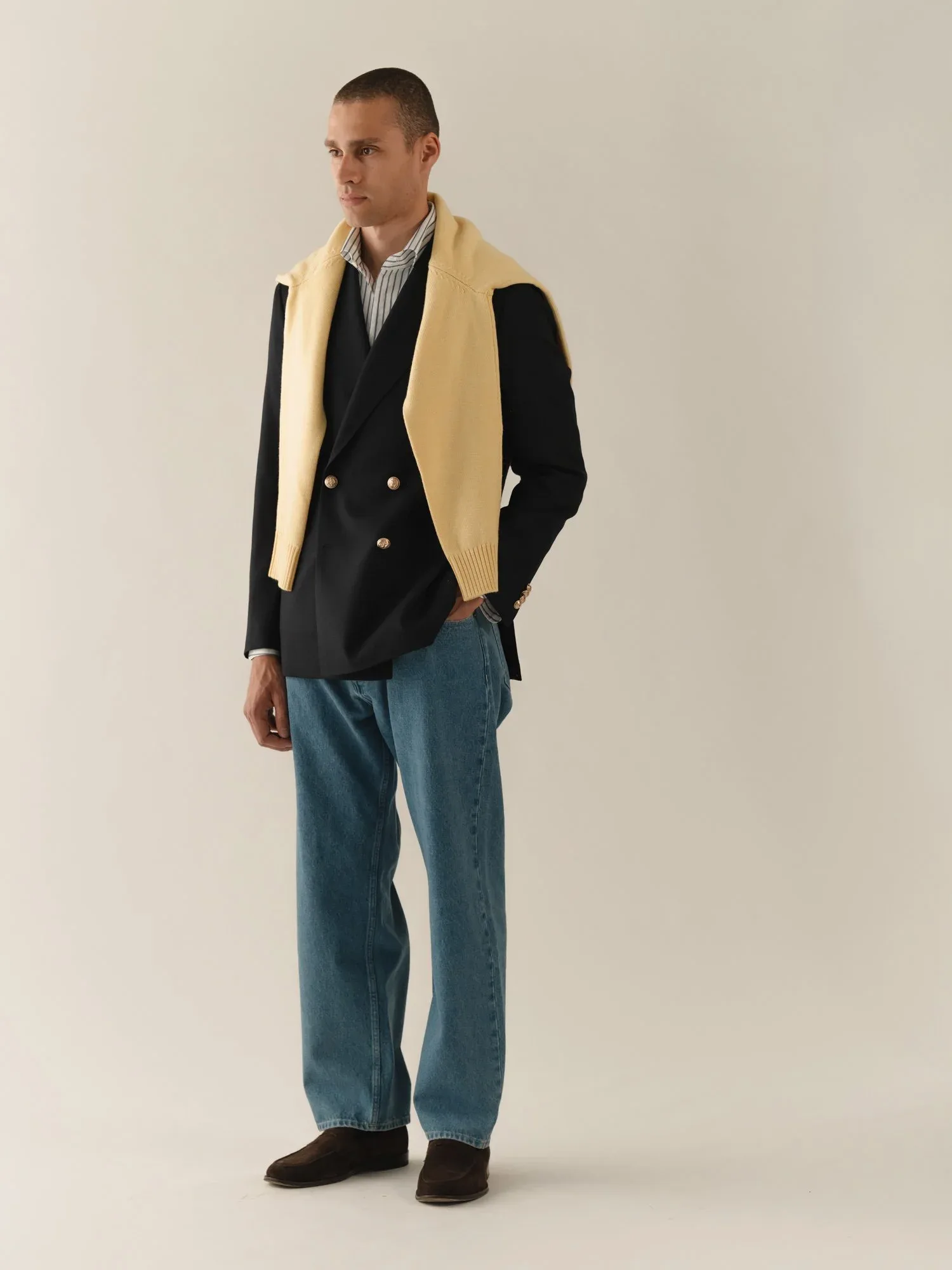 Navy double-breasted blazer with gold buttons over yellow knitwear and jeans