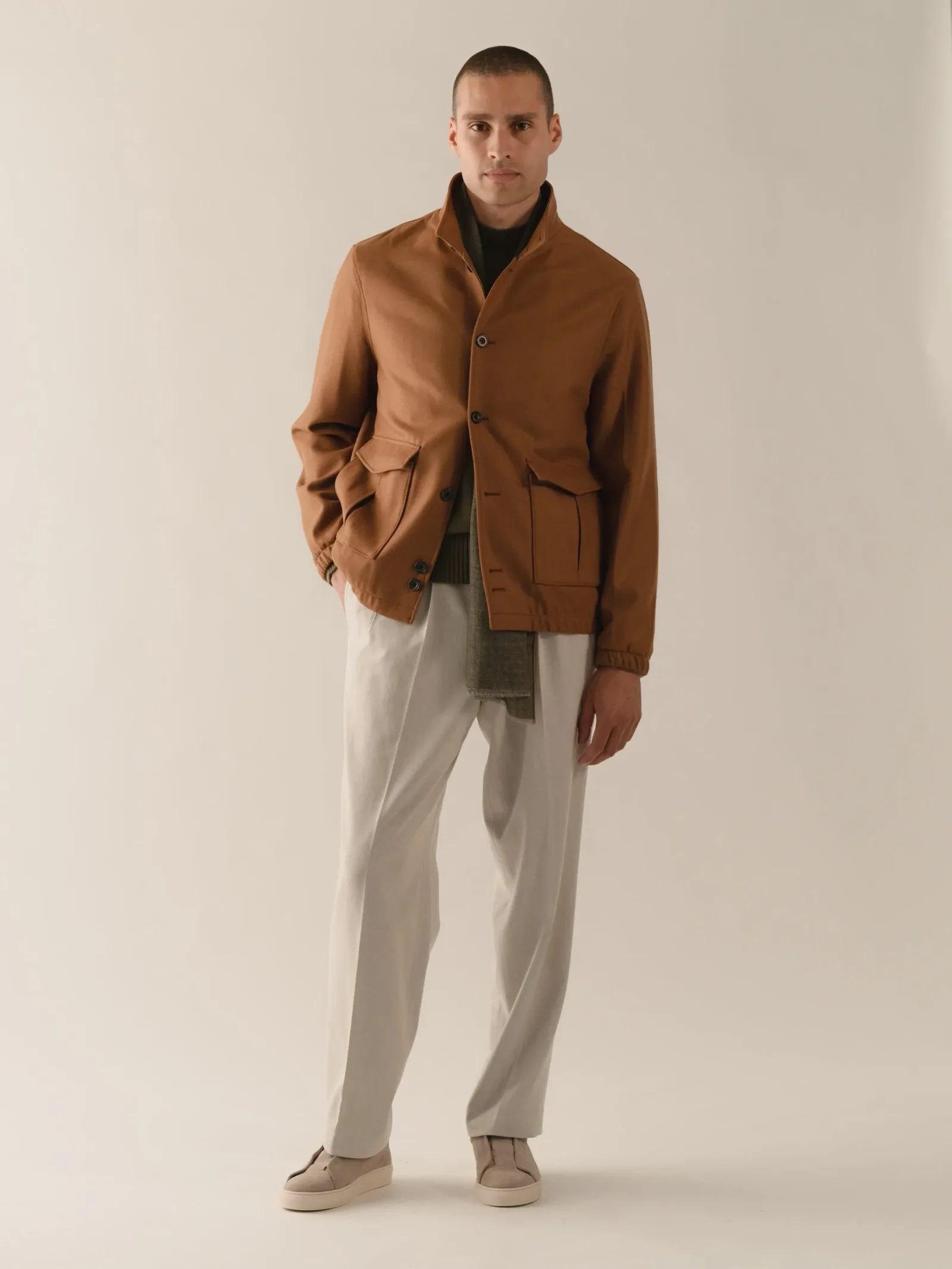 Cognacbrun field jacket over mørk rullekrave og lyse uldbukser