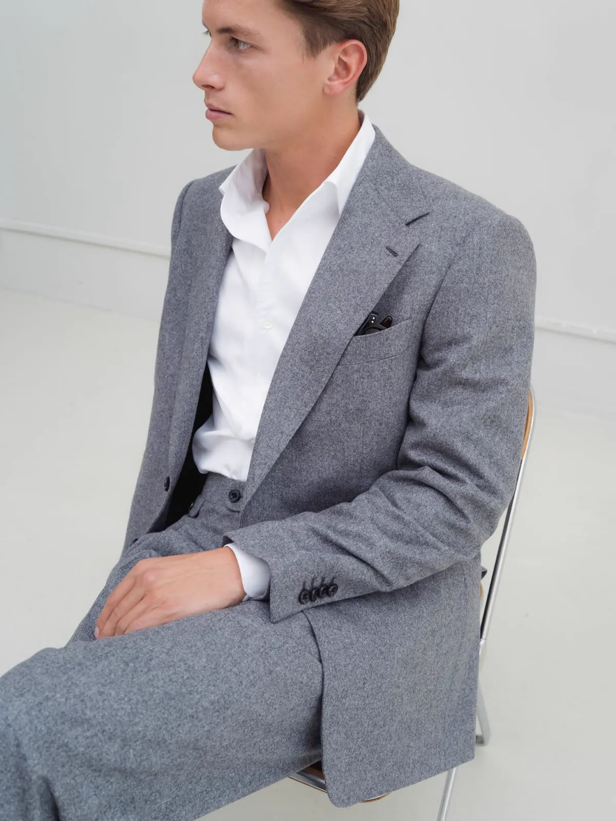 Man in a grey jacket and white shirt, seated