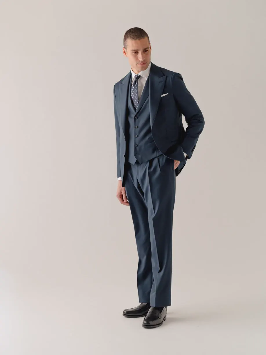 Man in a navy three-piece suit with hand in pocket