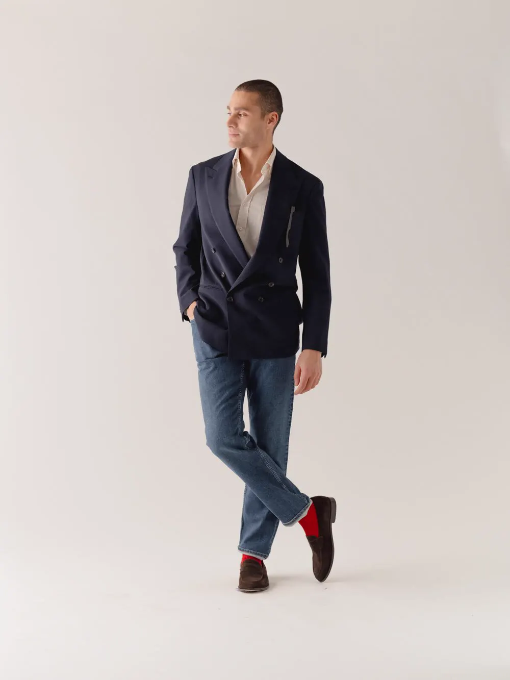 Mand i marineblå dobbeltradet blazer, jeans og røde sokker