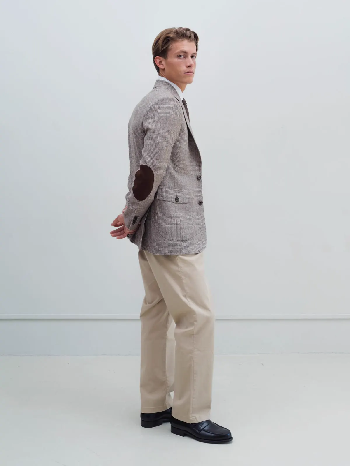 Mand i ternet blazer med albuelapper og beige bukser, set fra siden