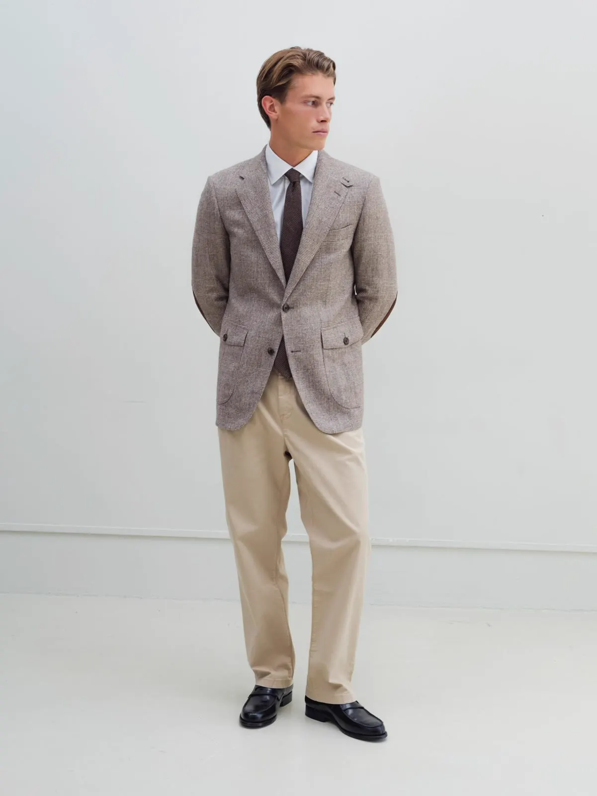 Mand i grå blazer, skjorte og slips med beige bukser