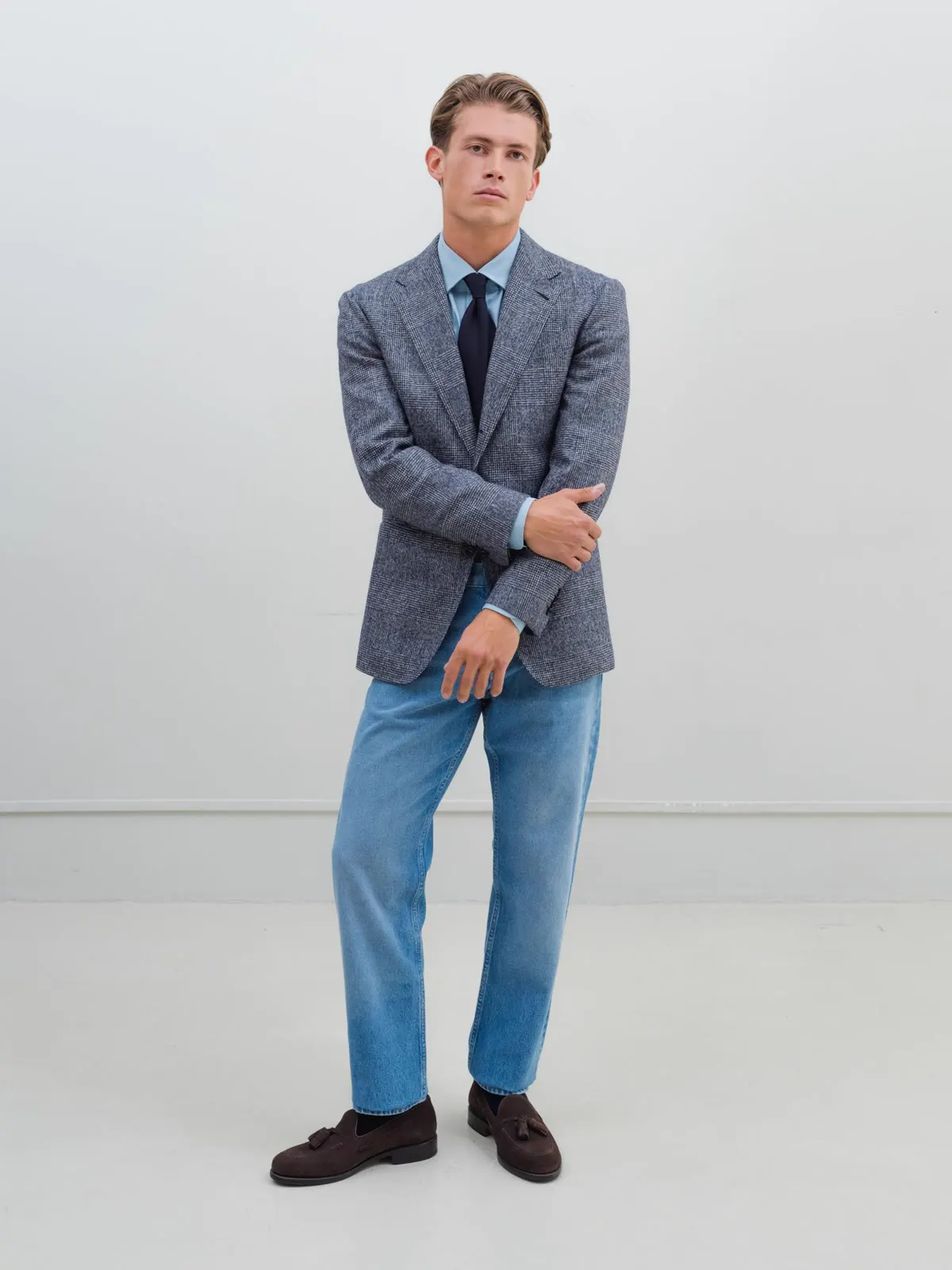 Mand i blå tweedblazer, lyseblå skjorte, slips og jeans