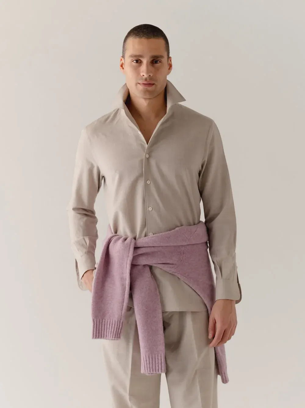 Mand i beige skjorte med lilla strik bundet om livet