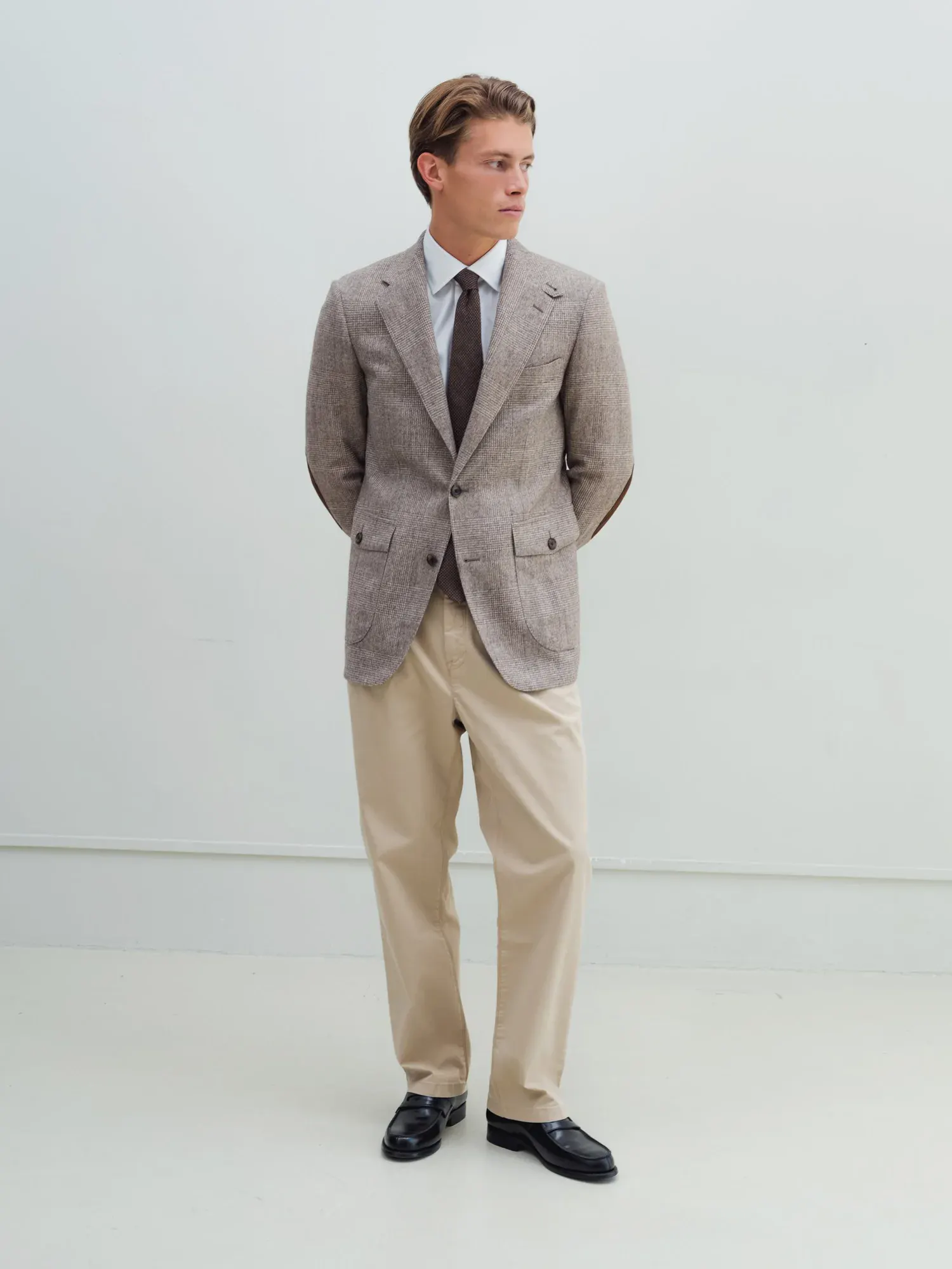 Mand i beige chinos, gråbrun blazer og sorte loafers