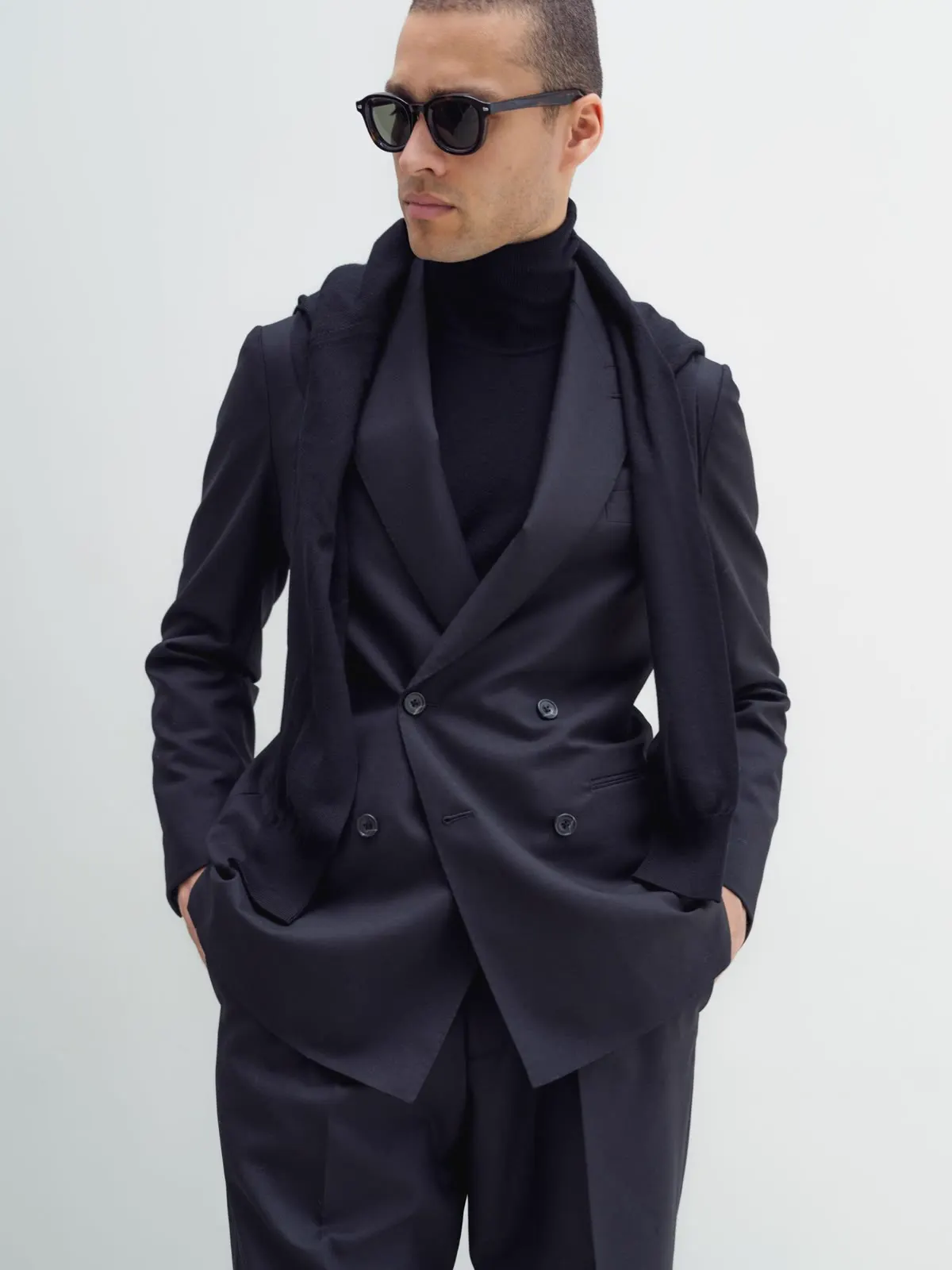 Man in a dark double-breasted suit, black roll neck and sunglasses