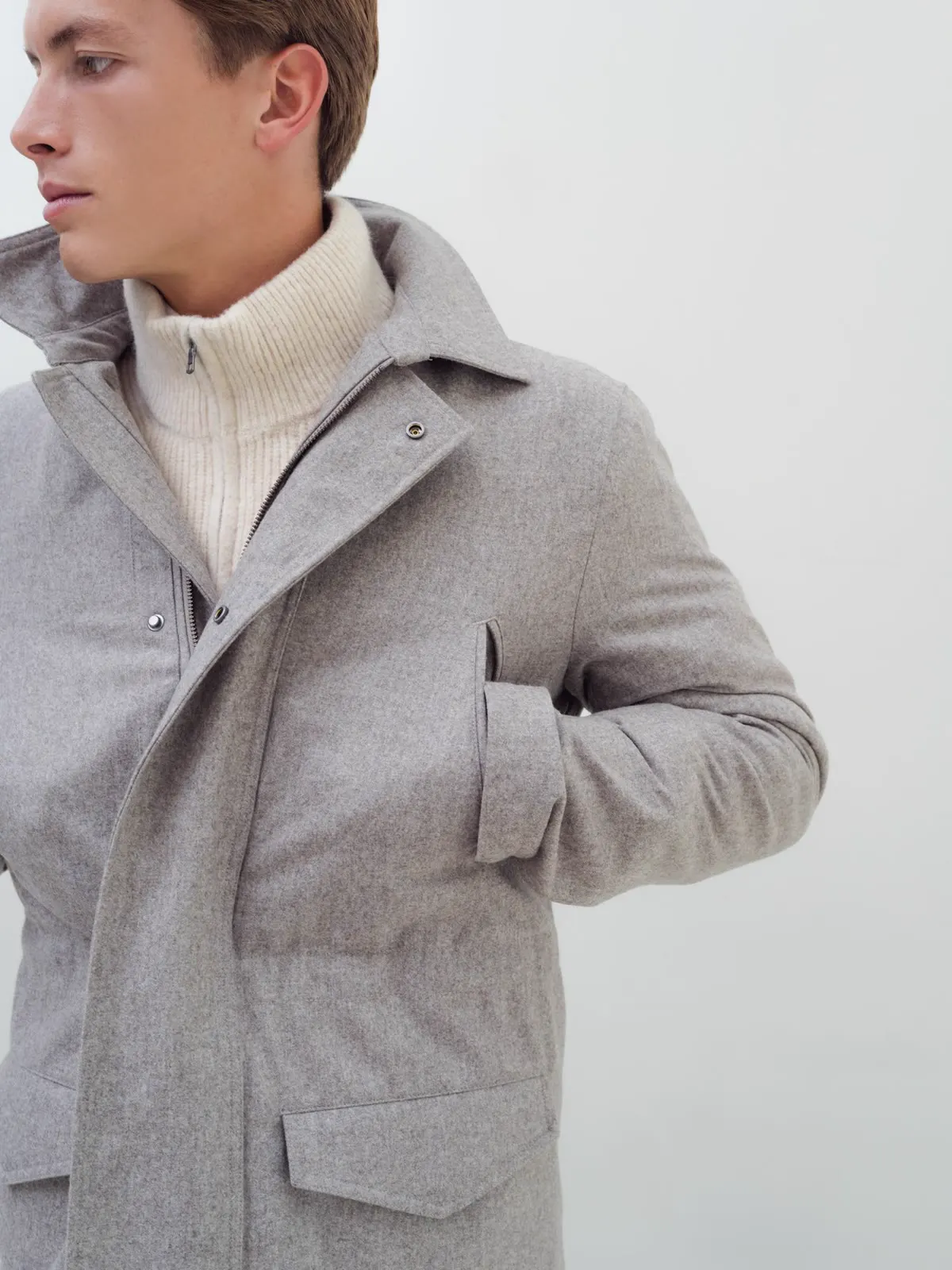 Grå field jacket med ståkrave og klaplommer over lys strik