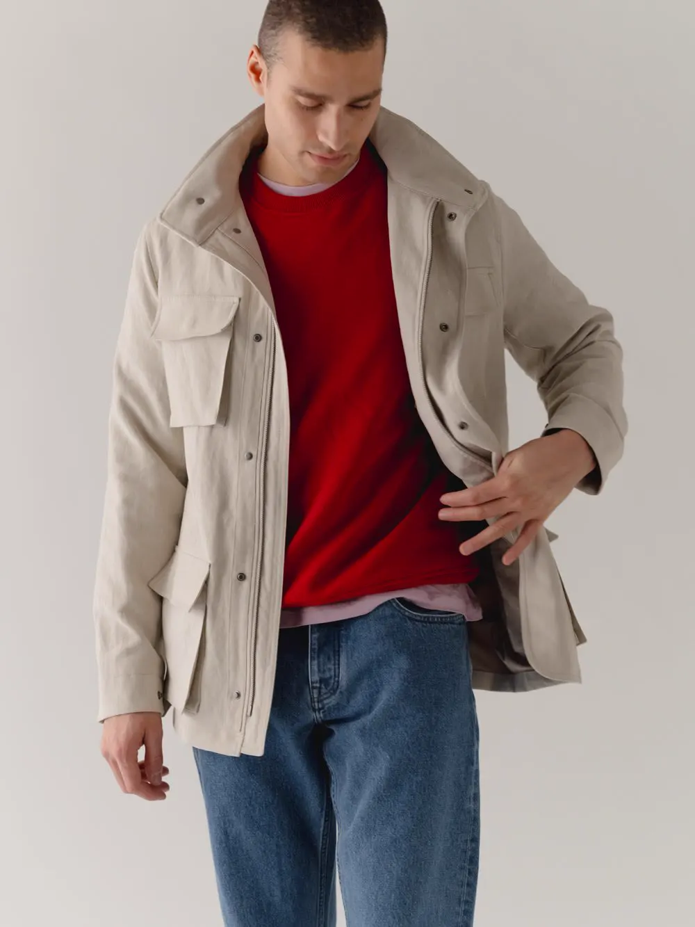 Mand i lys field jacket over rød strik og jeans