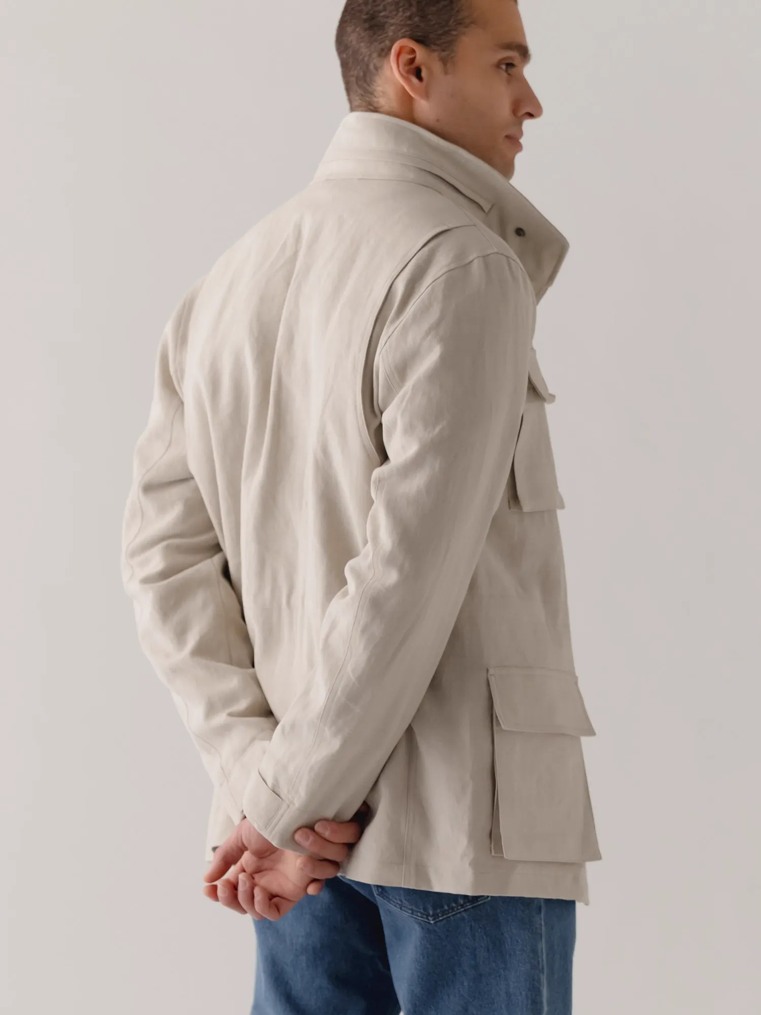 Man seen from behind in a light beige field jacket with a high collar