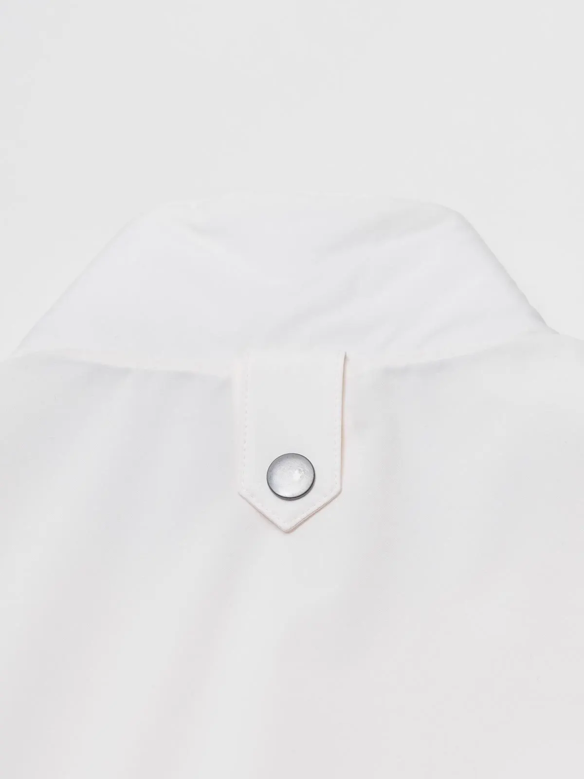 Close-up of a strap with a press stud on a white gilet