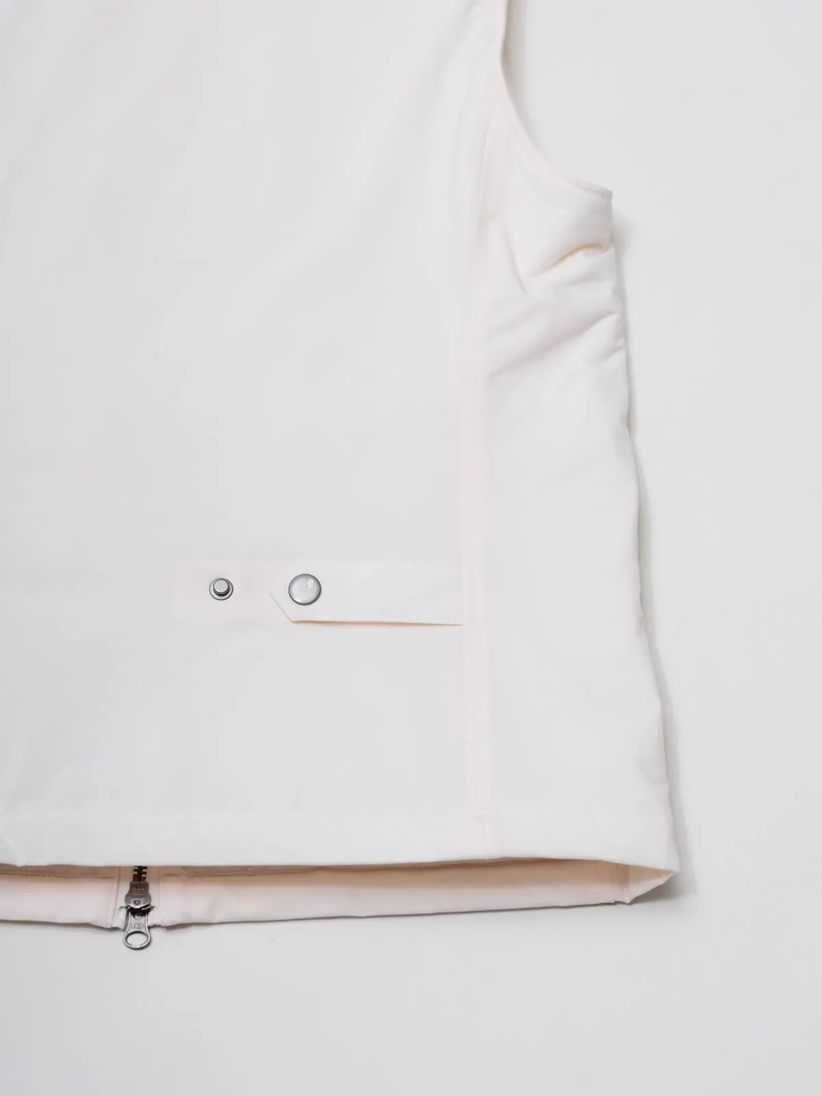 Close-up of the pocket and the zip at the bottom of a white gilet
