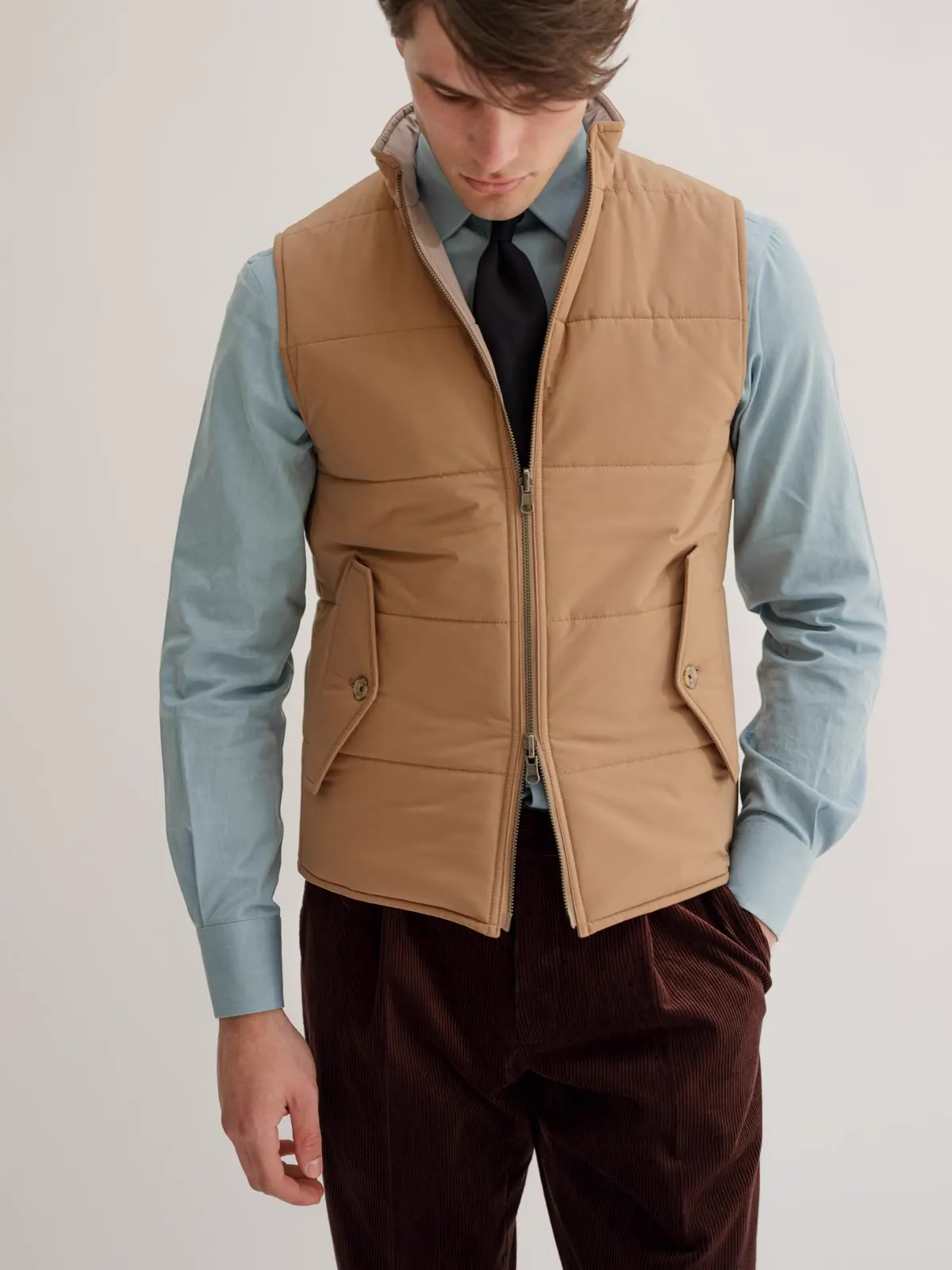 Camel quilted gilet over a light blue shirt and tie