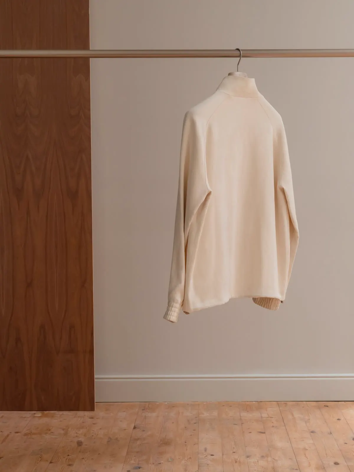 Light Harrington jacket hung on a rail, seen from behind