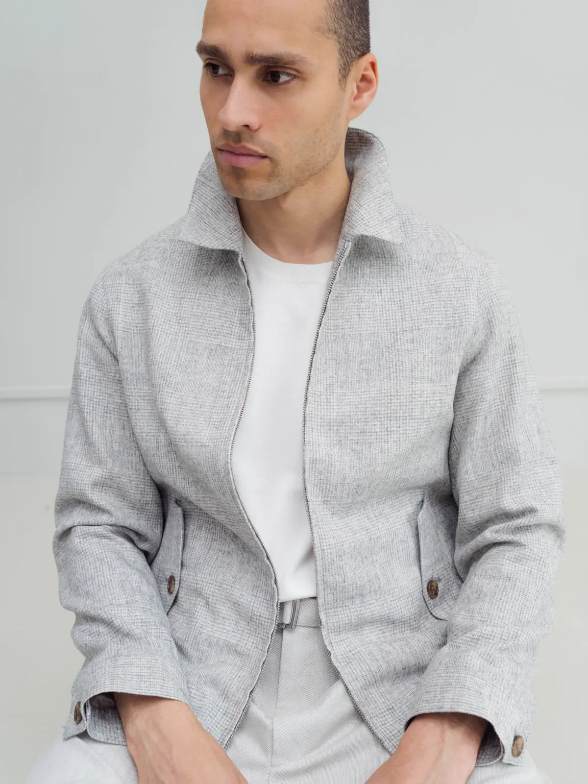Man in a light grey short jacket with a stand collar and a white T-shirt