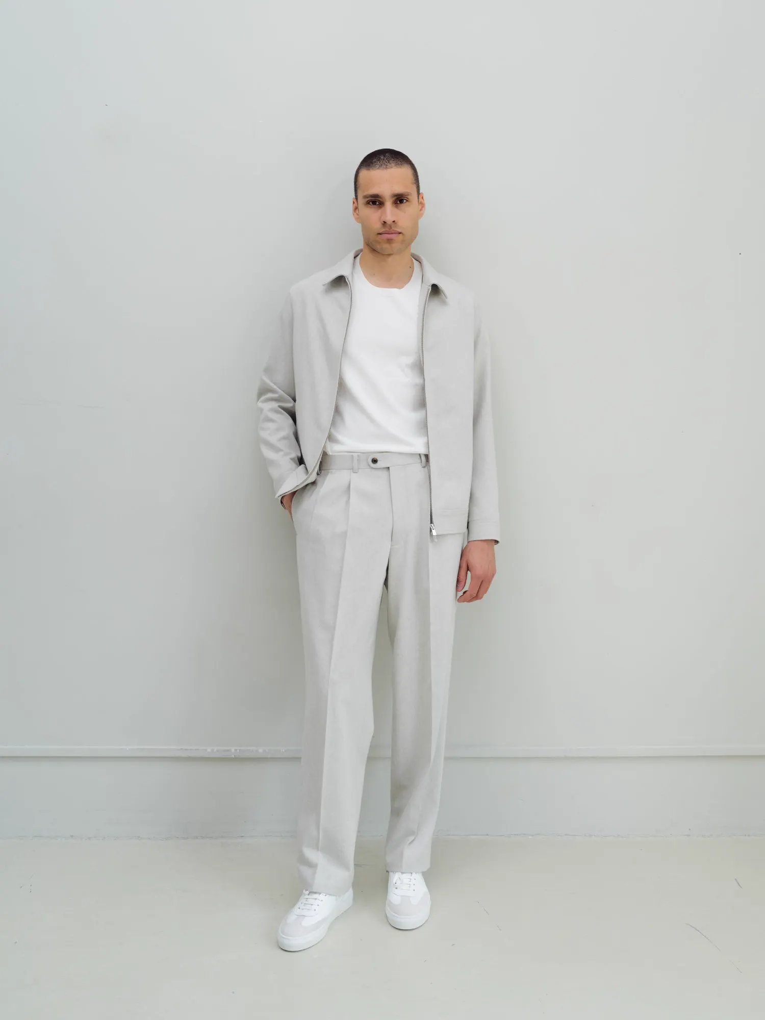 Man in a light grey jacket and matching trousers, full length