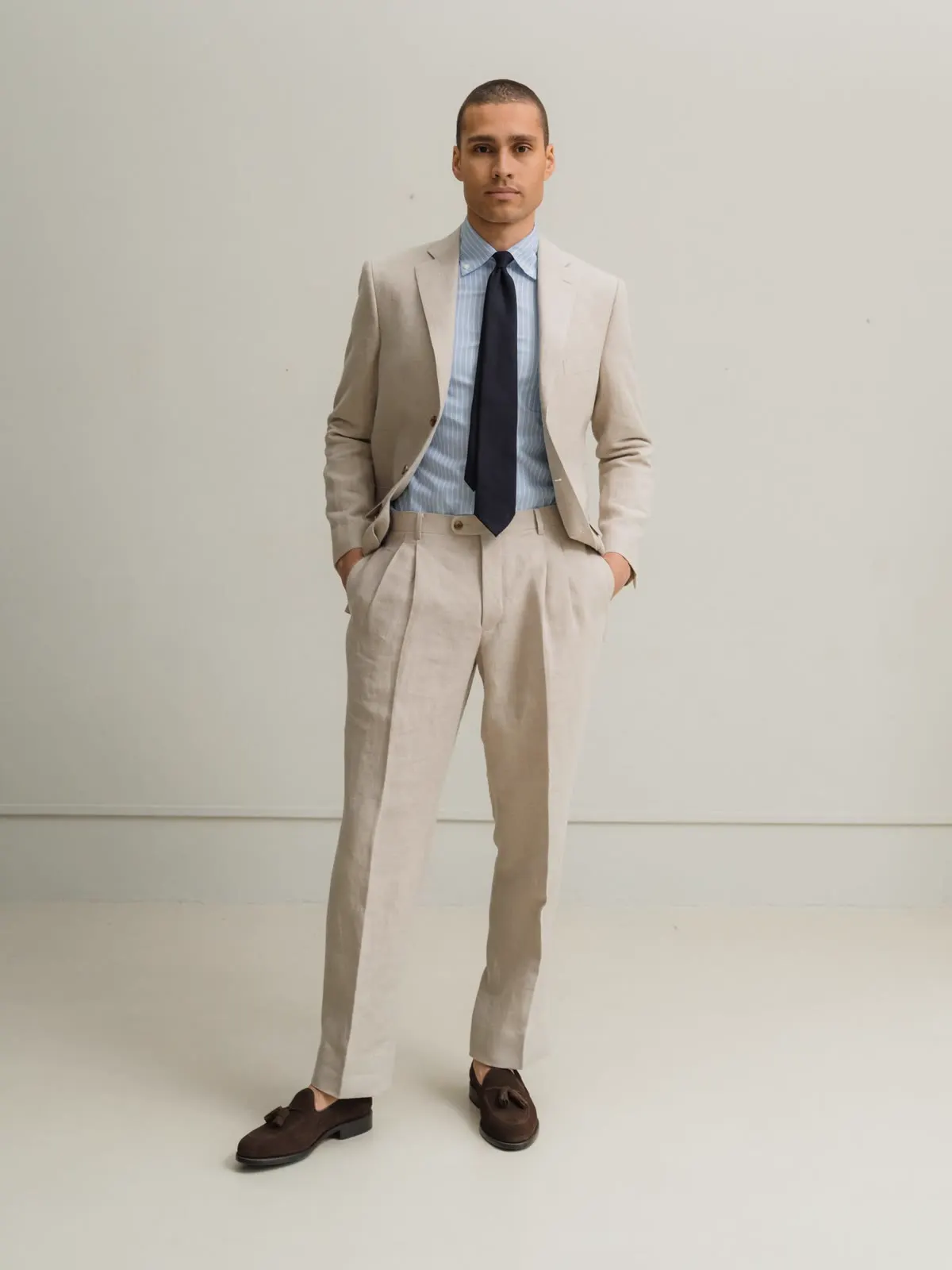 Man in a sand-coloured linen suit with a light blue shirt and dark tie