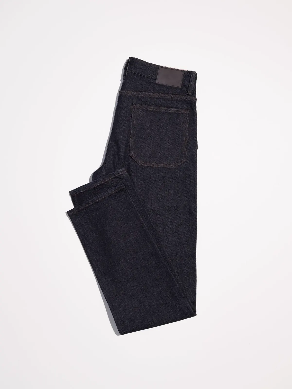 Dark indigo jeans folded on a white background