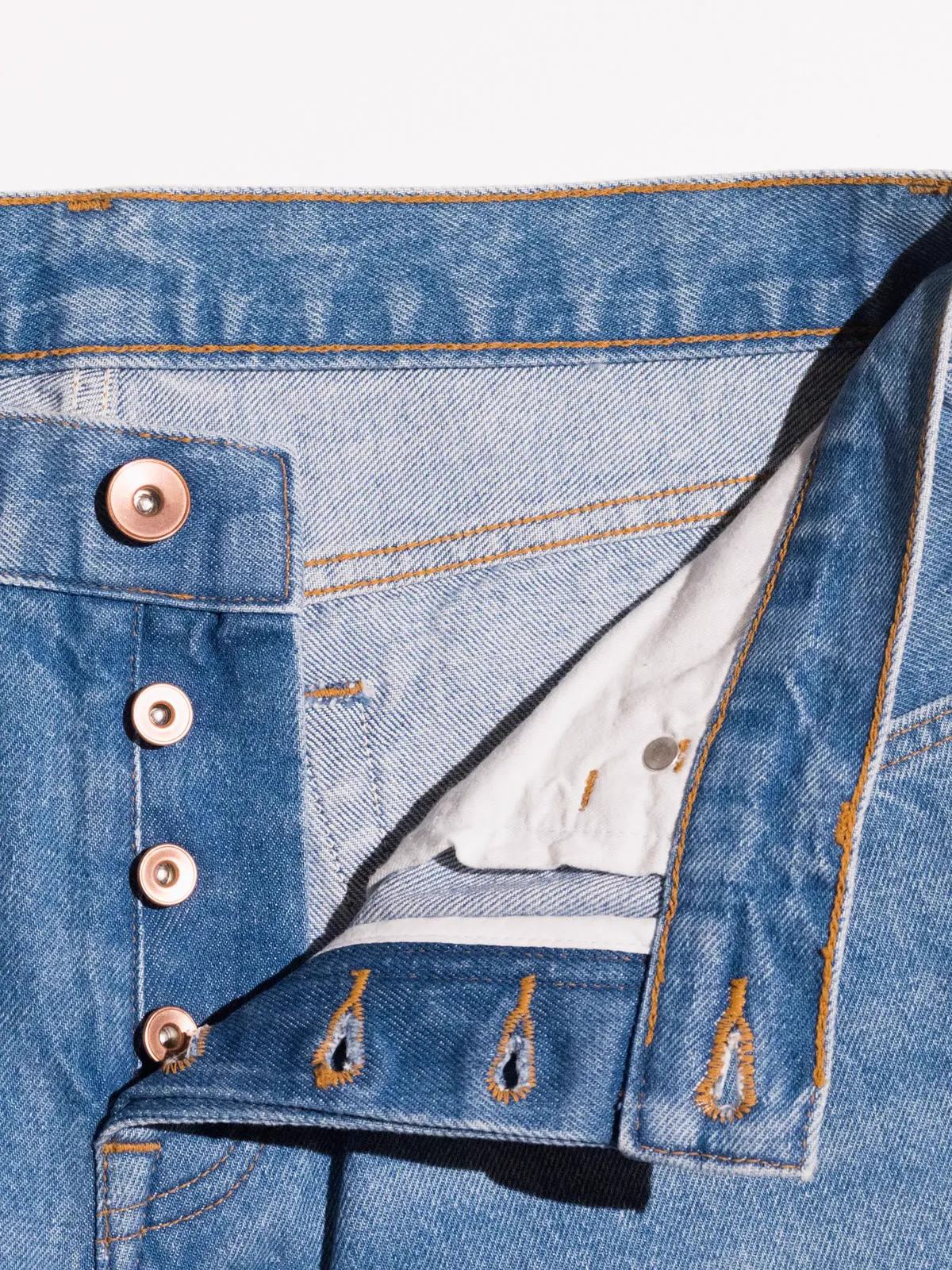 Close-up of the button fly on a pair of light jeans