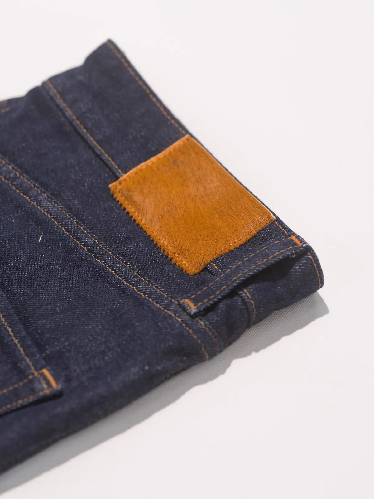 Nærbillede af læderrygmærket på et par rå indigo jeans