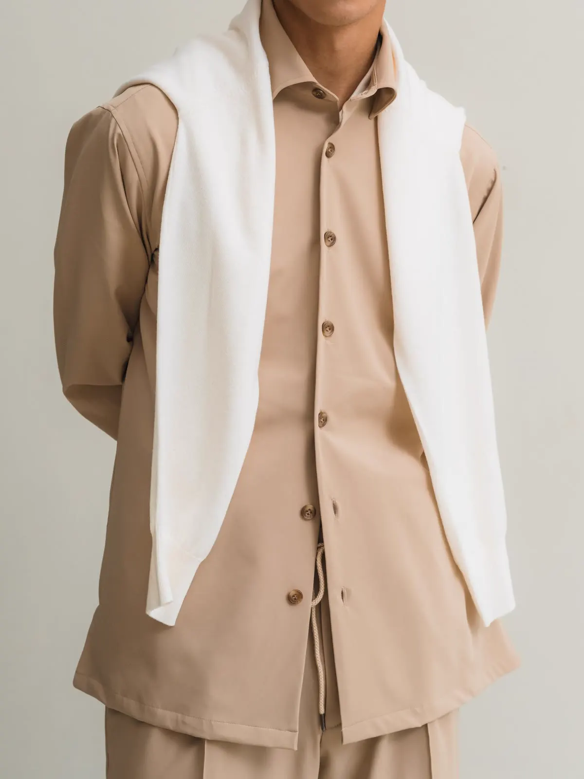 Light brown overshirt with a white sweater over the shoulders
