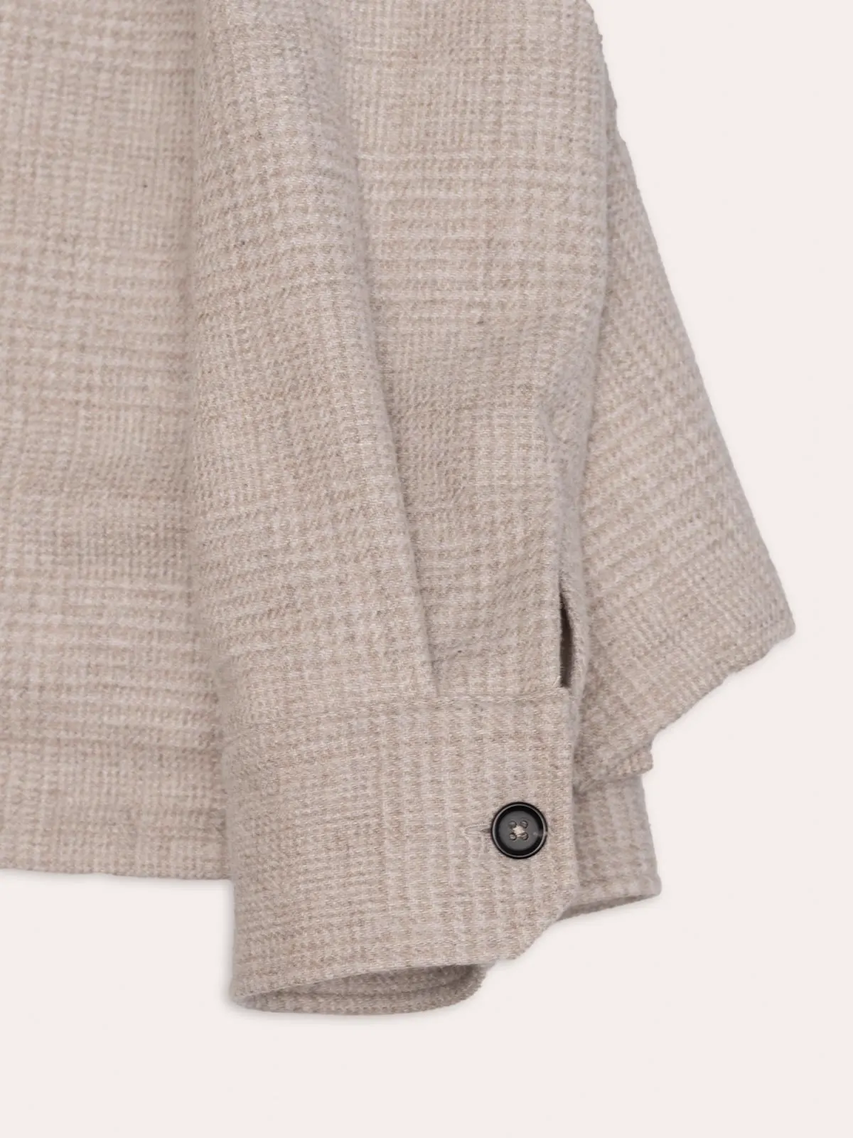 Close-up of the sleeve on a light checked shirt jacket with a button on the cuff