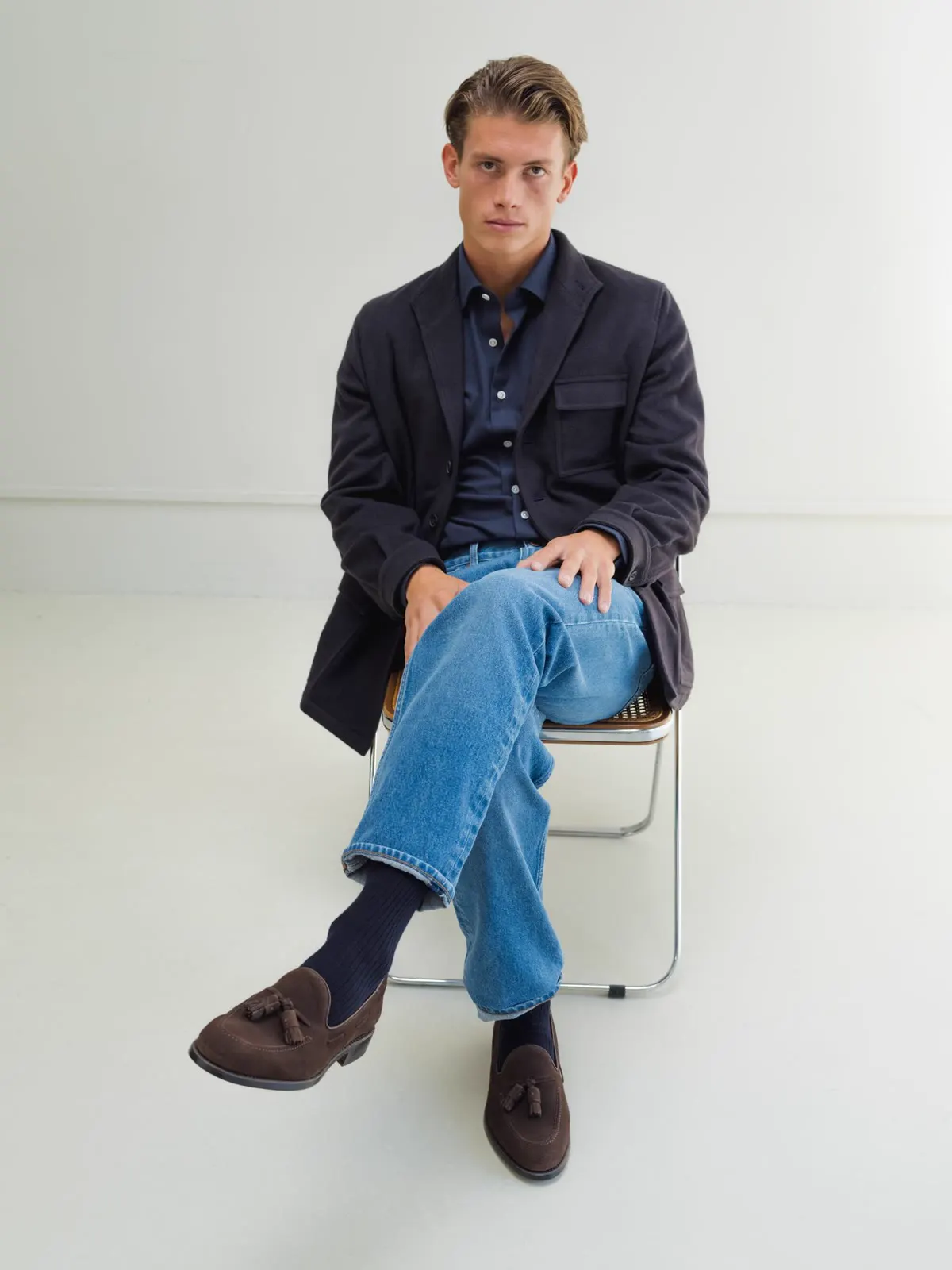 Man on a chair in a dark overshirt and jeans