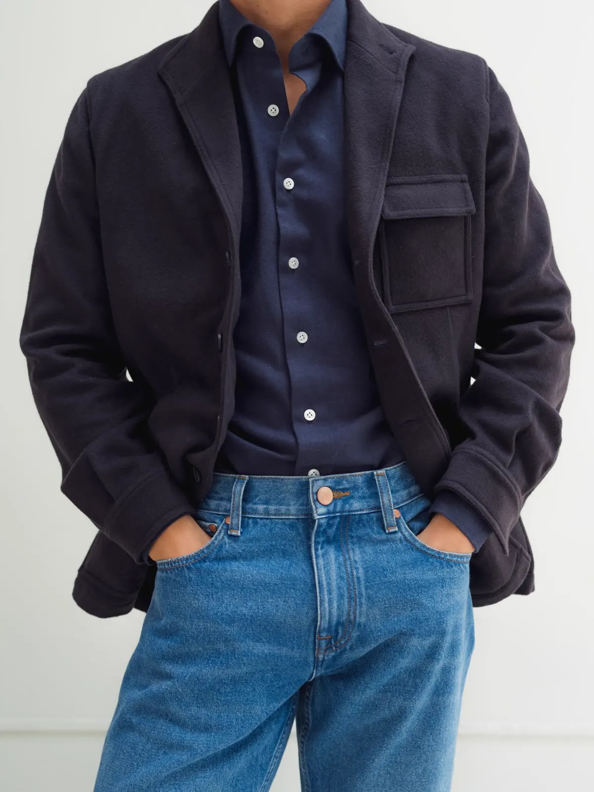 Dark overshirt with a chest pocket over a dark blue shirt and jeans