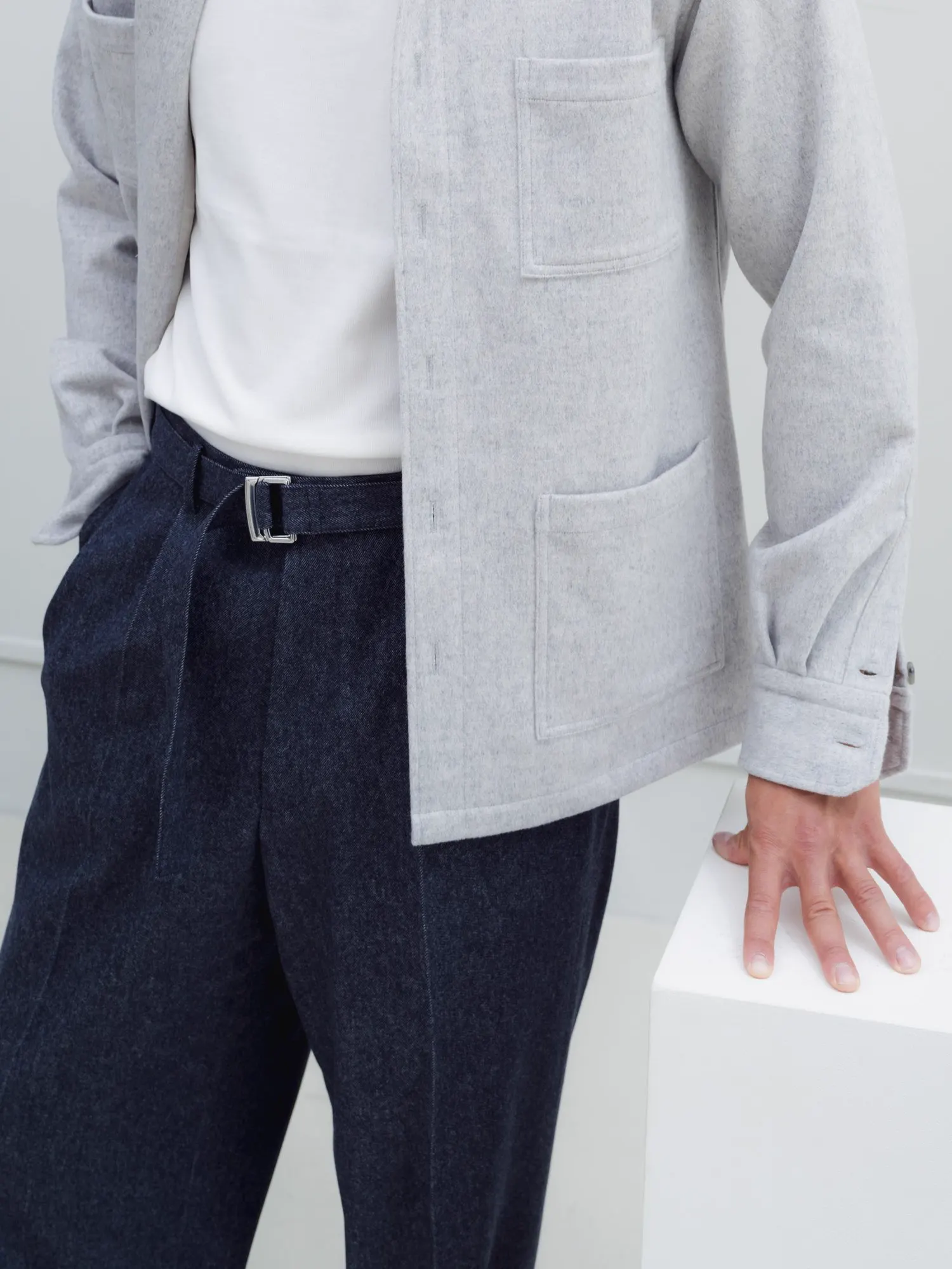 Light grey overshirt with a pocket, worn with dark blue trousers and a belt