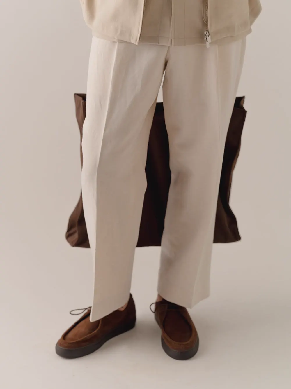 Light trousers with turn-ups and brown shoes with a brown bag