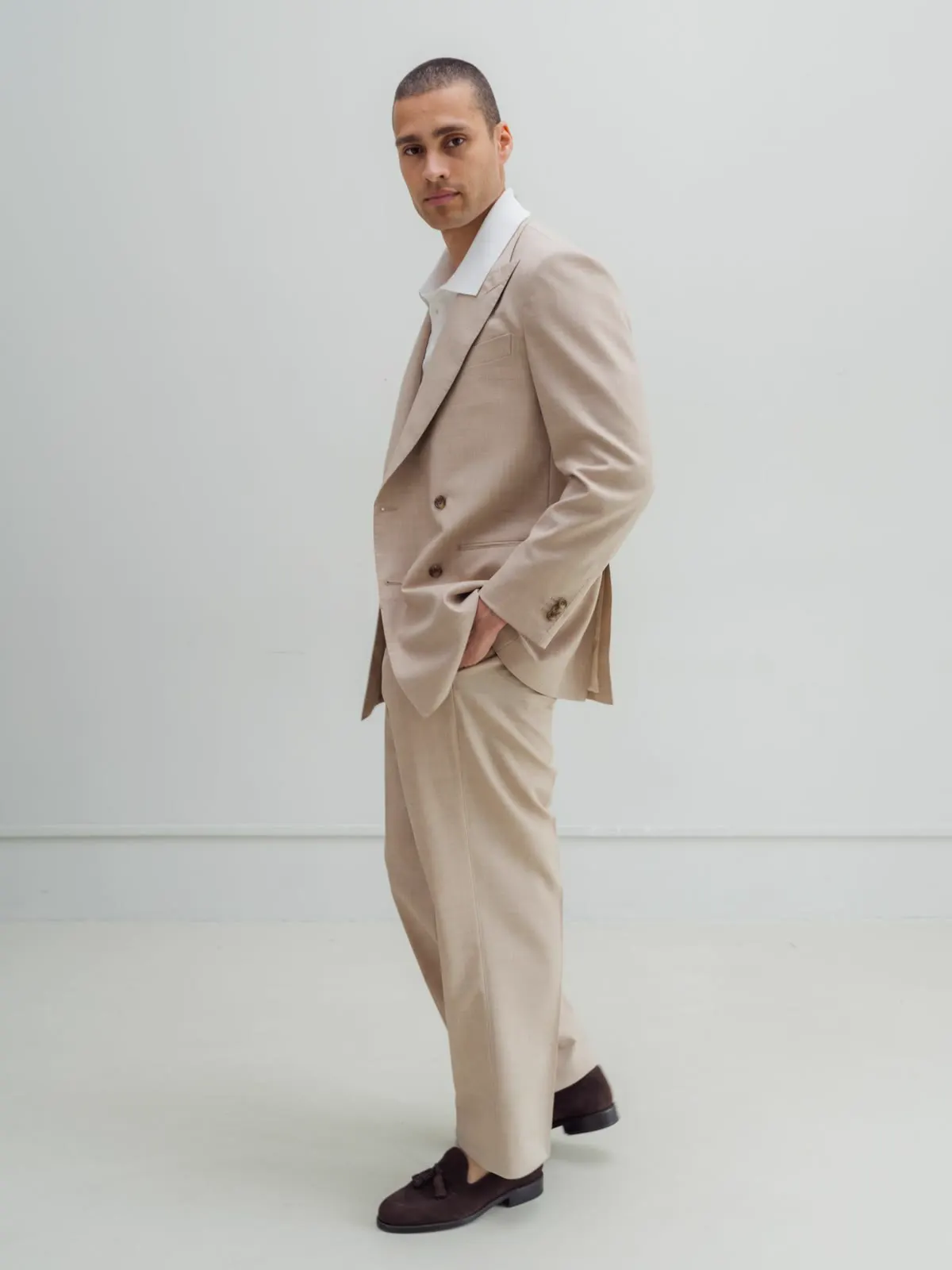 Man in a sand-coloured suit, seen from the side