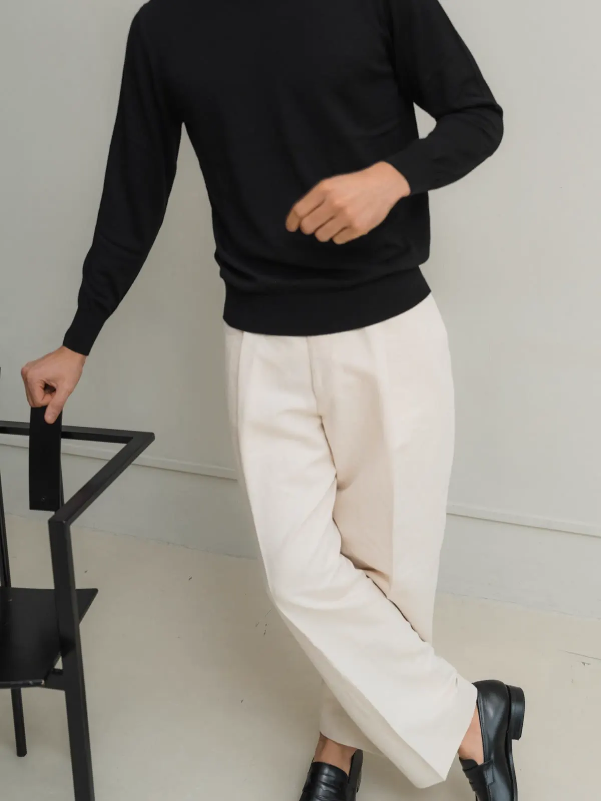 Light trousers and black knit by a chair