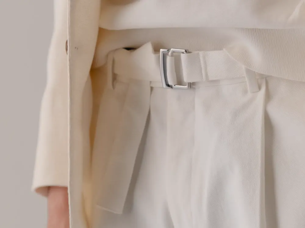 Close-up of a side adjuster with buckle on light trousers