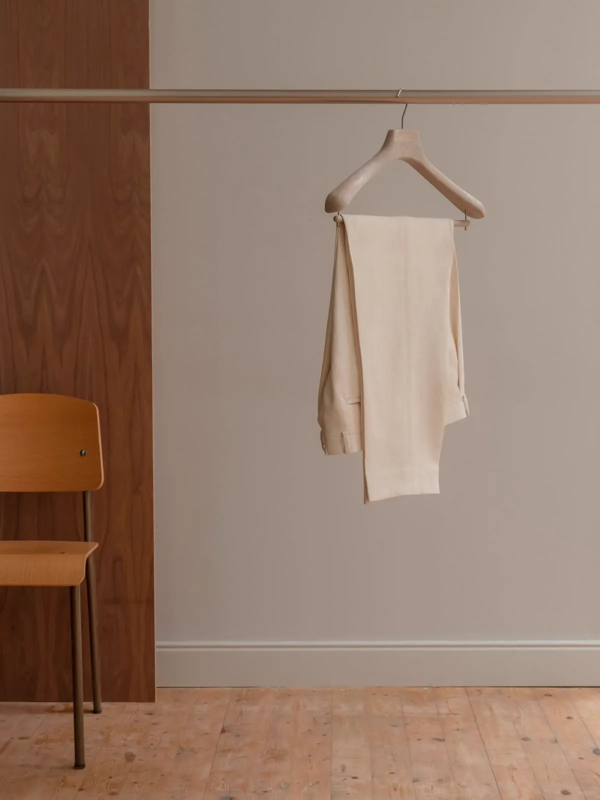Light trousers hanging on a hanger in front of wood panelling