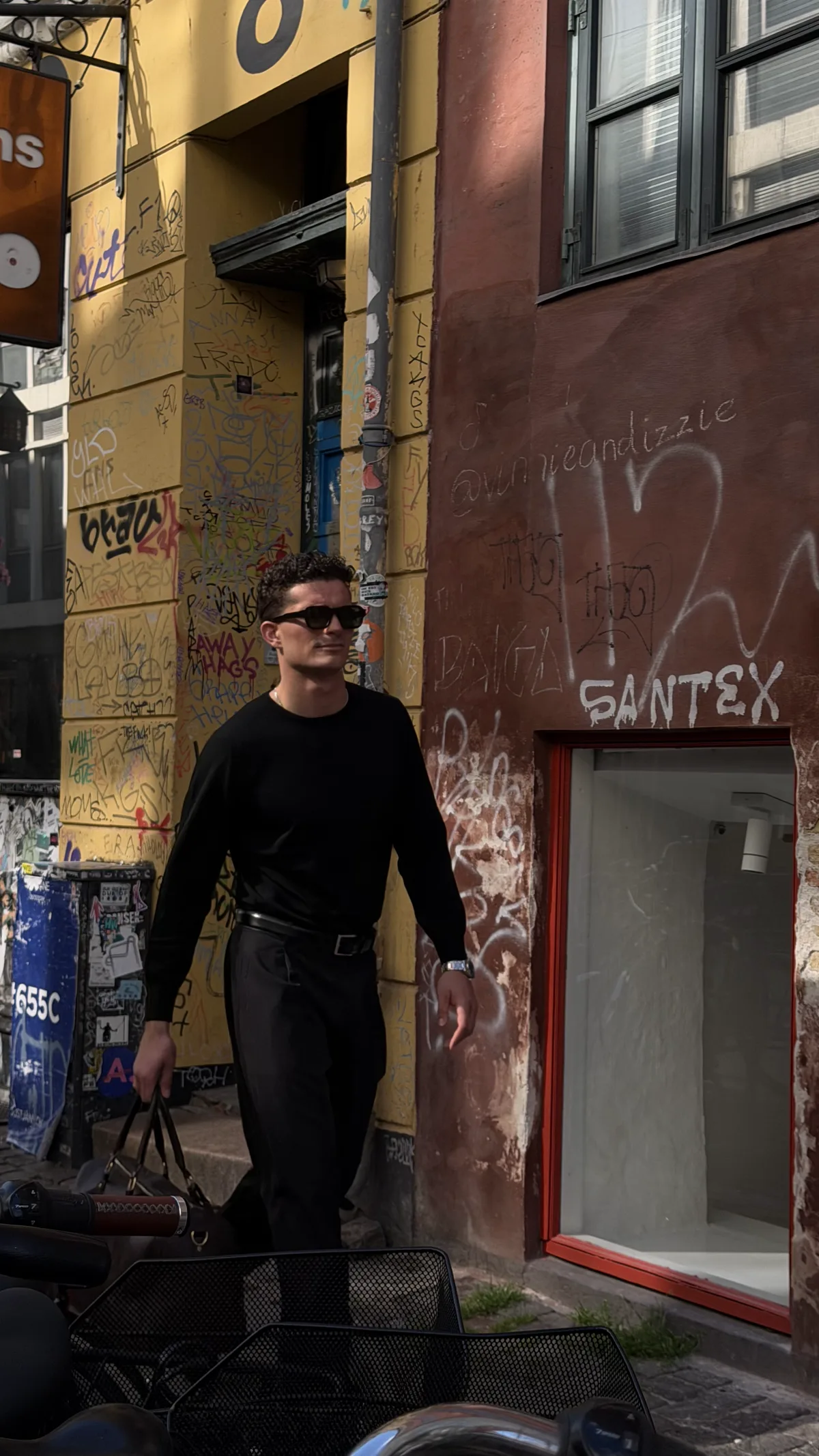 Sort merino crewneck foran graffiti-facade i København