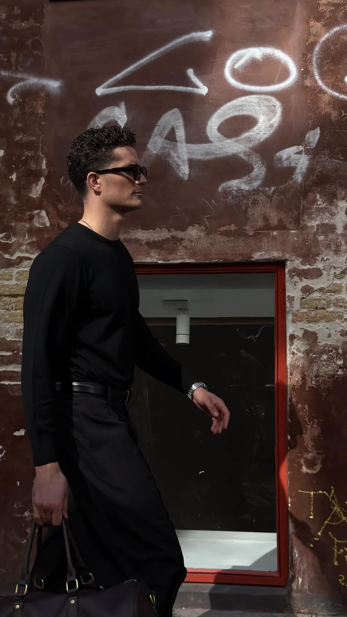 Sort merino crewneck i profil foran rå facade