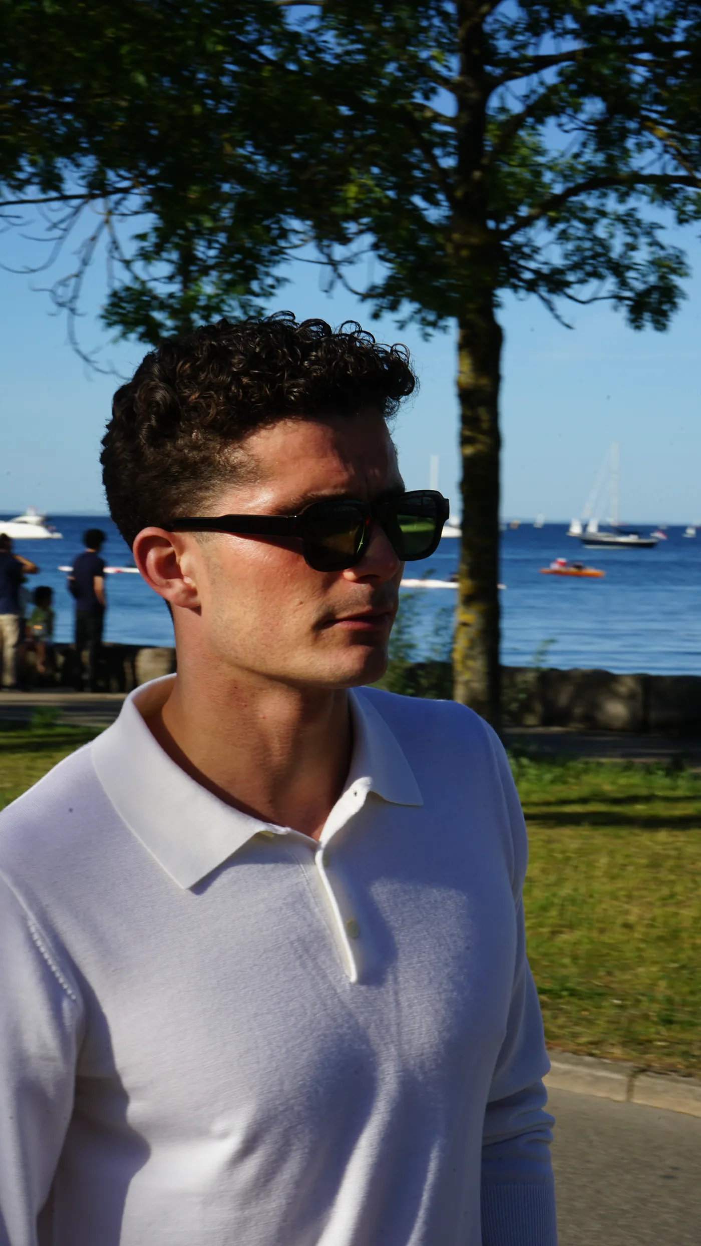 Hvid langærmet merino-polo på model ved vandet, tæt på