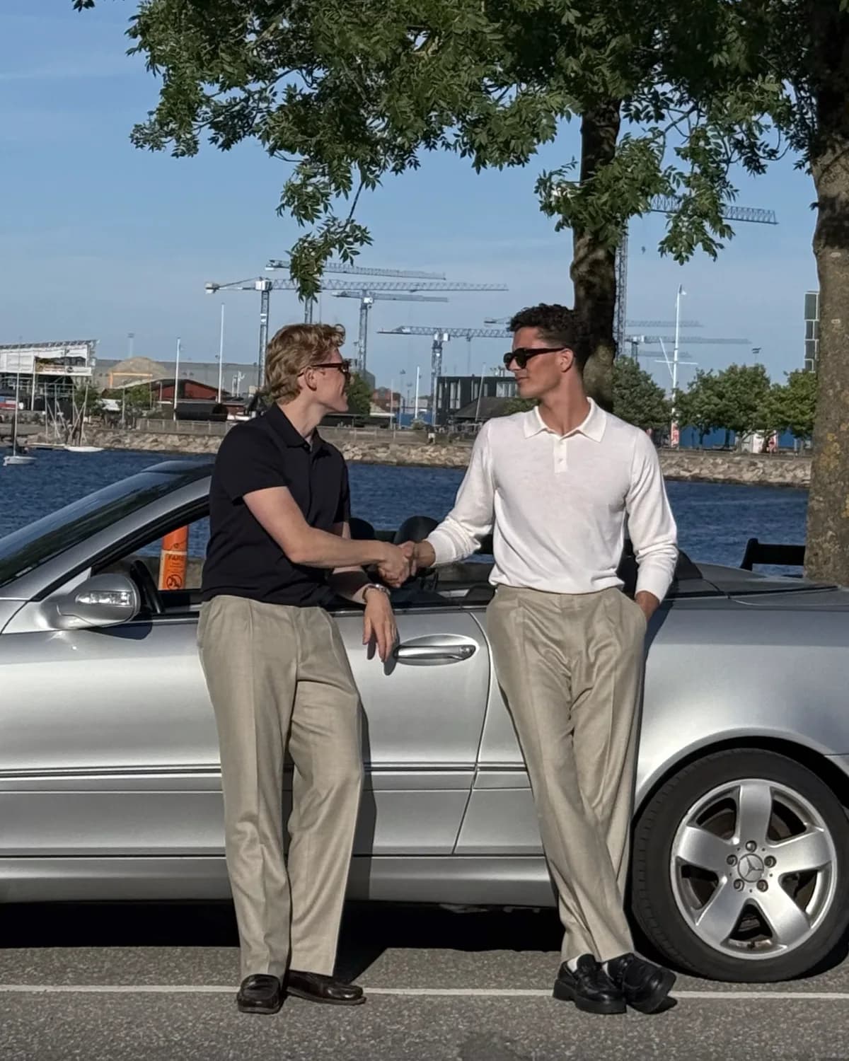 To mænd ved en Mercedes cabriolet, den ene i hvid langærmet merino-polo