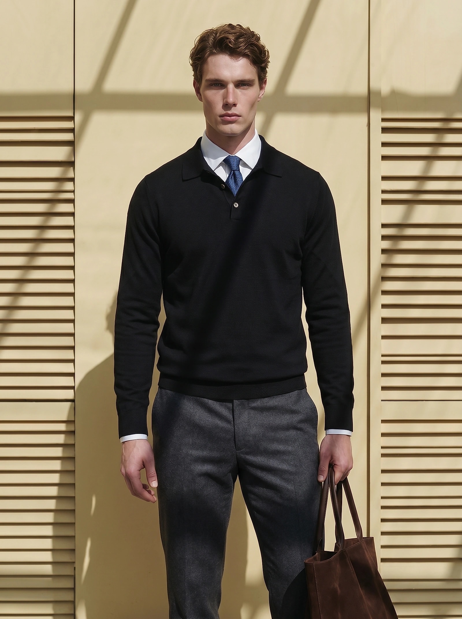 Man in a black merino wool polo knit over a white shirt and tie
