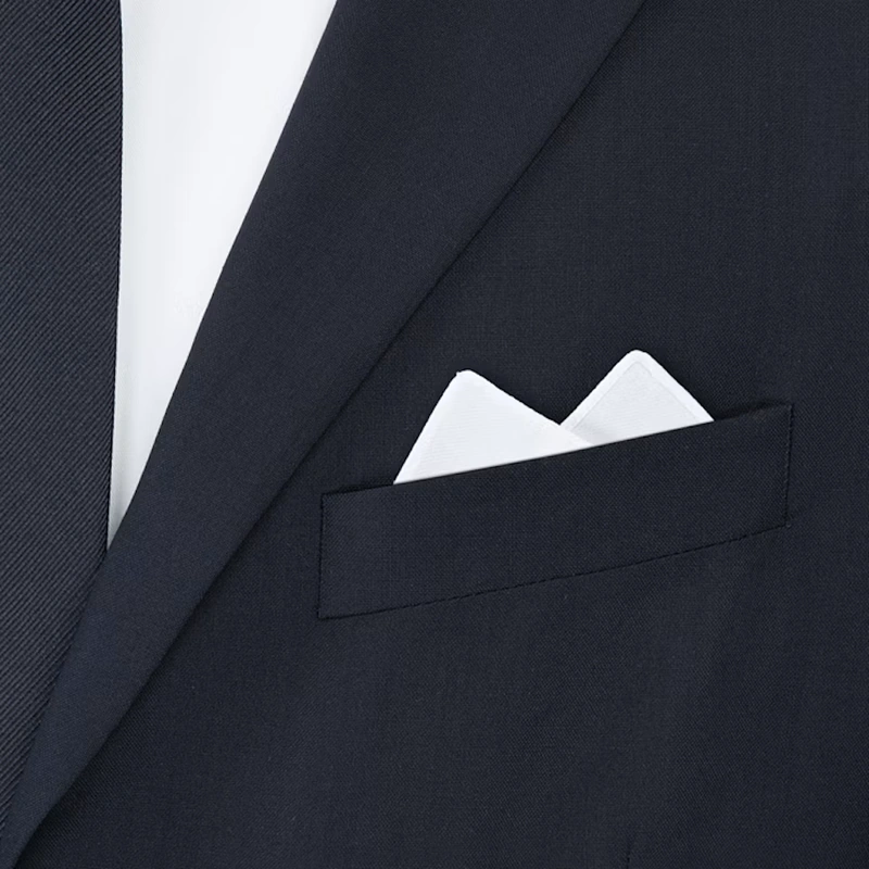 White pocket square with two points up in the breast pocket of a navy jacket