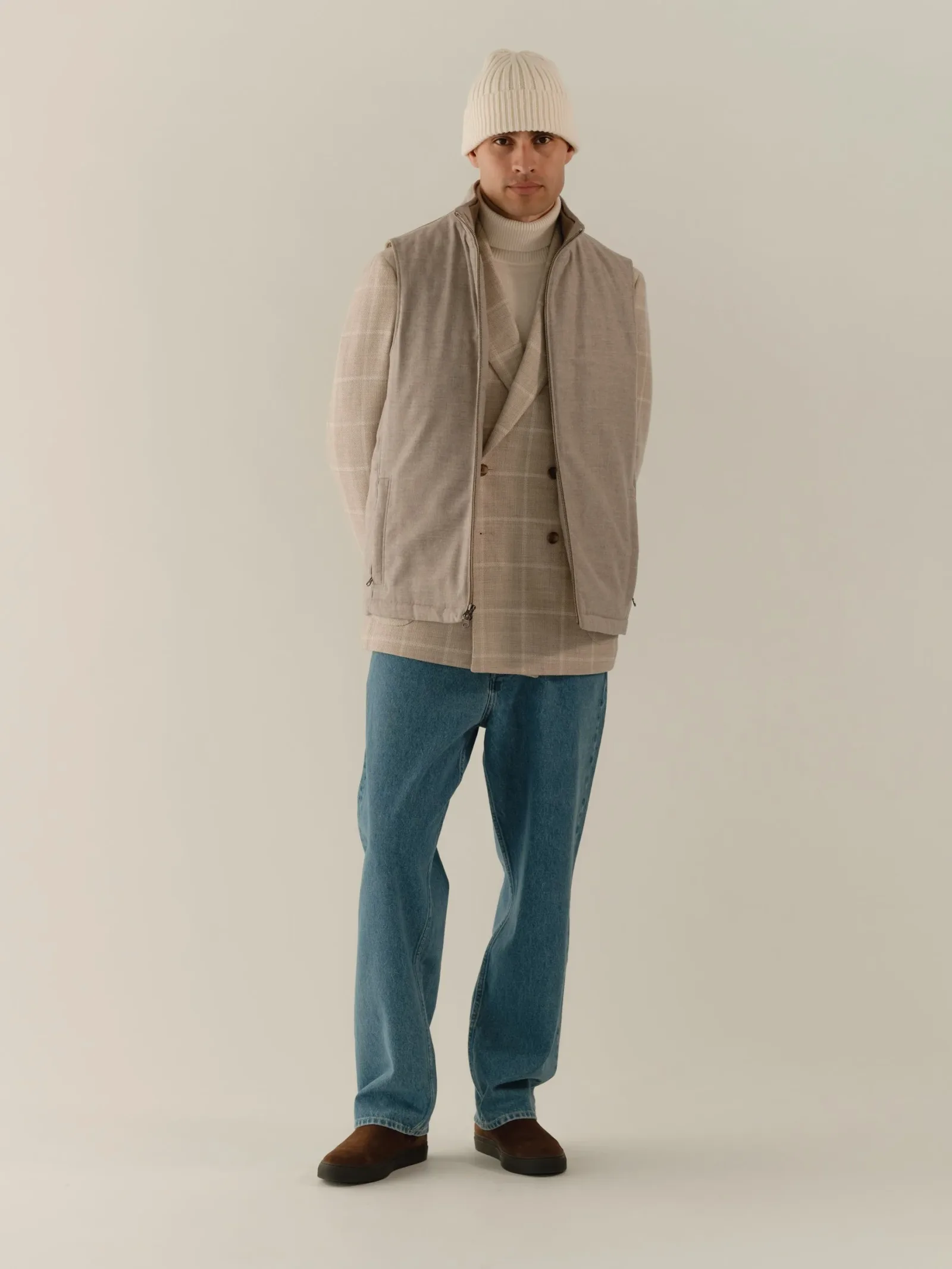 Beige windowpane blazer over jeans, layered with a gilet and beanie