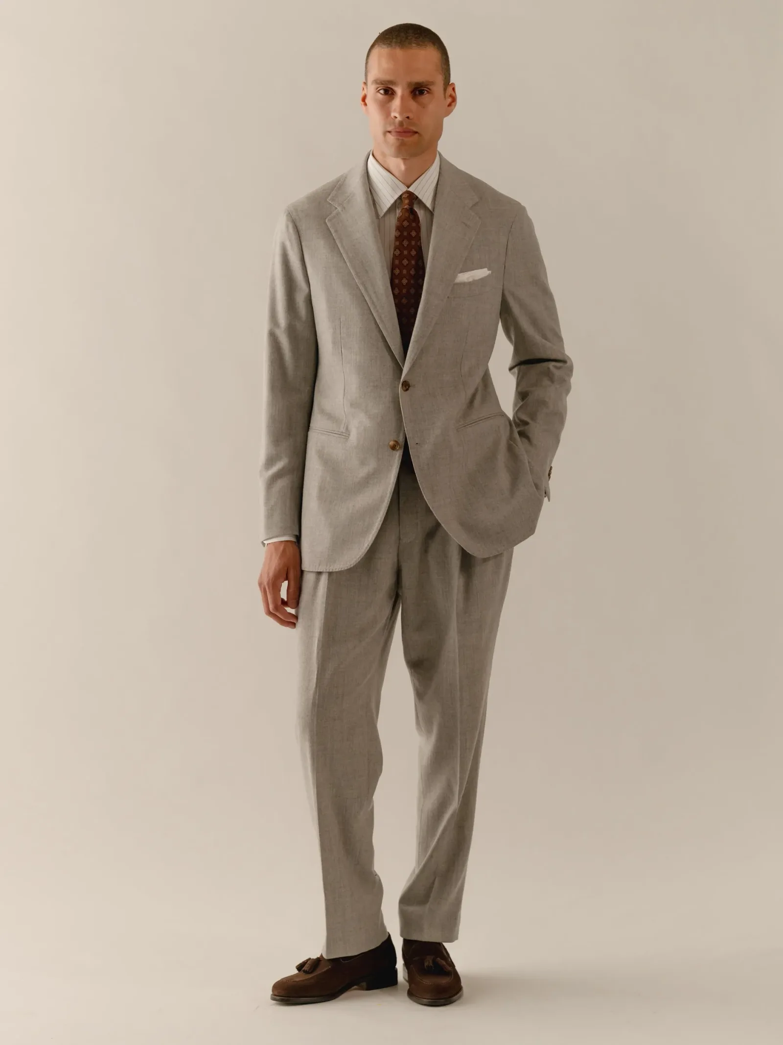 Man in a light grey suit with a brown tie