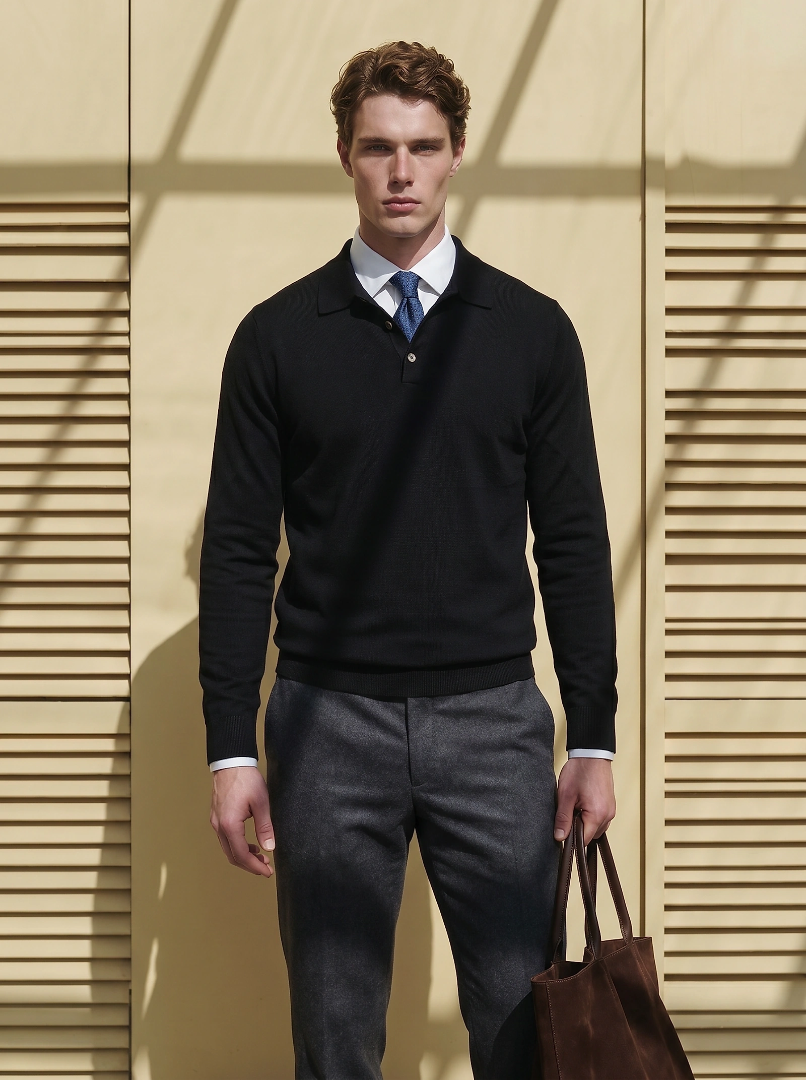 Man in a black merino wool polo knit over a white shirt and tie